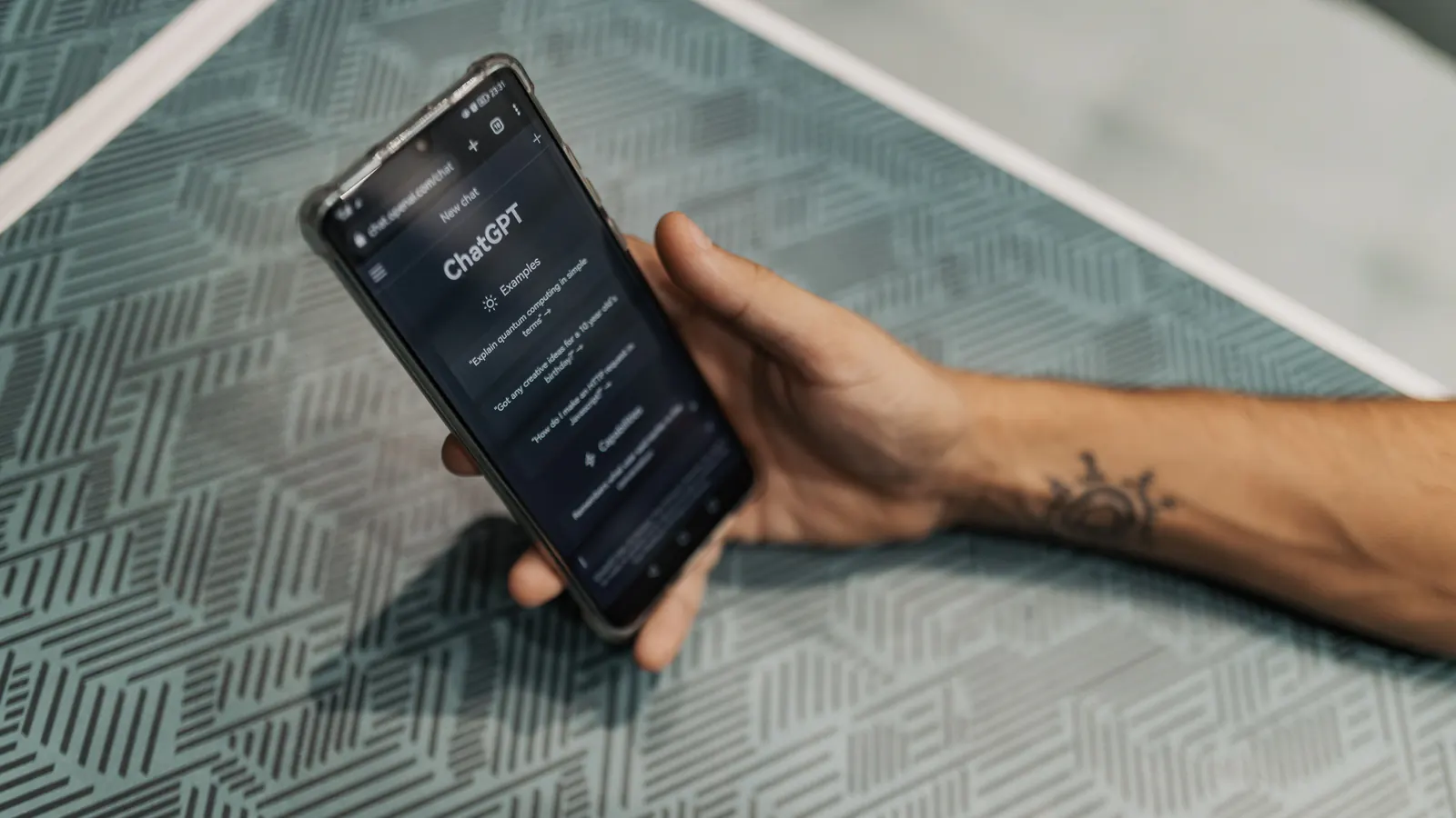 A hand holds a phone with the ChatGPT app open on the screen.